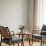 Two chairs facing each other across a small table in a bright neutral room, calm, no text